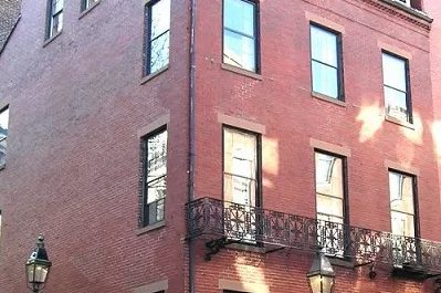 A brick row house with an iron balcony