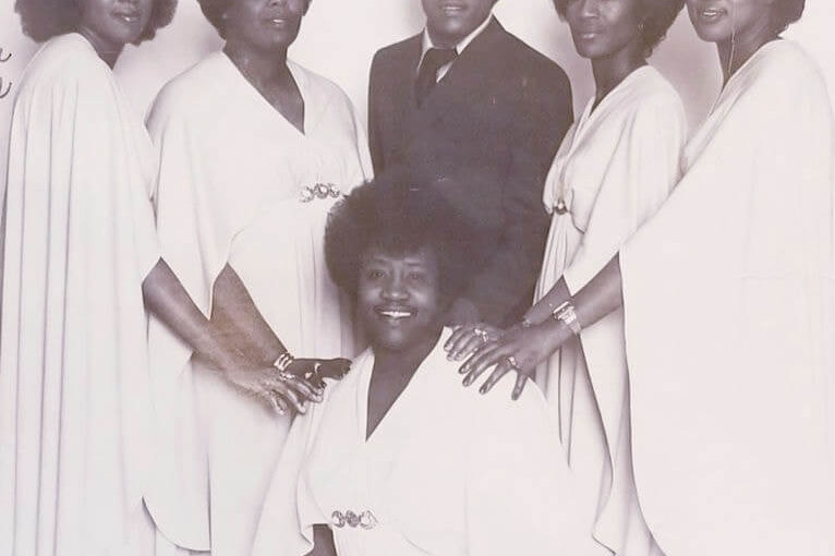 International Gospel Singers including Ray Reddick Five women in white dresses and a man in a suit and wearing glasses