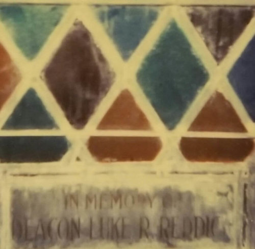 A stained glass window with an inscription reading "In memory of Deacon Luke R Reddick"