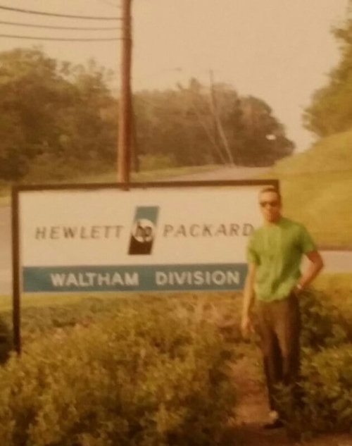 A man standing next to an HP sign reading Waltham Division