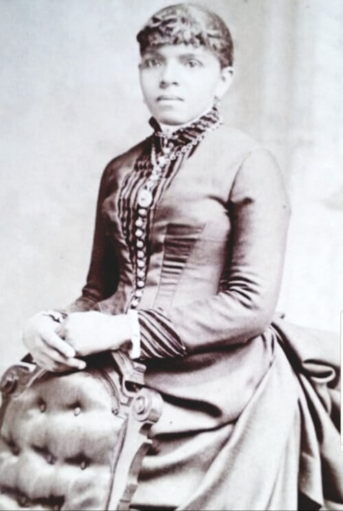 A Black woman of the 19th century wearing a fine dress