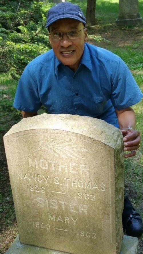 A man crouching behind a gravestone