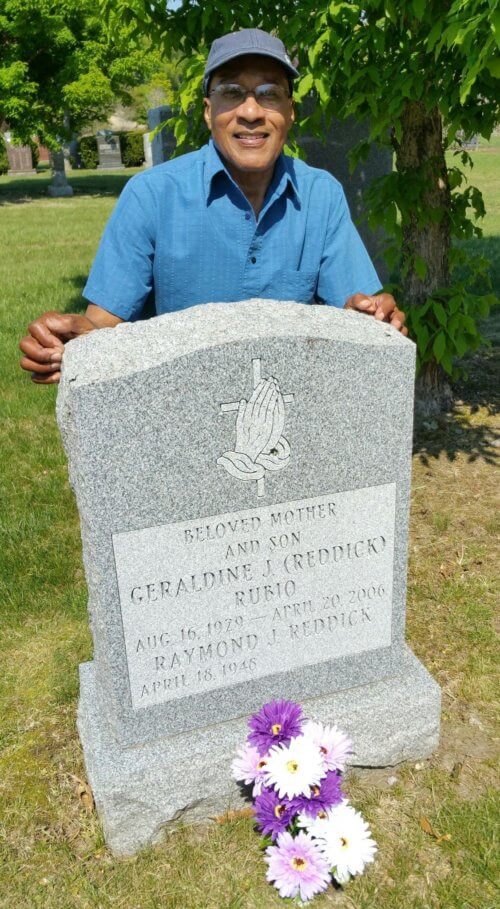 A man crouching behind a gravestone