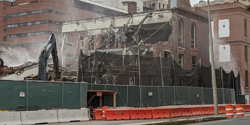 A historic building half collapsed with a crane knocking it down
