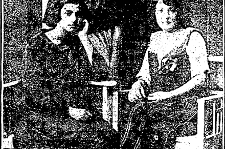 Photograph of two women sitting in chairs and a another woman and a man standing behind them.