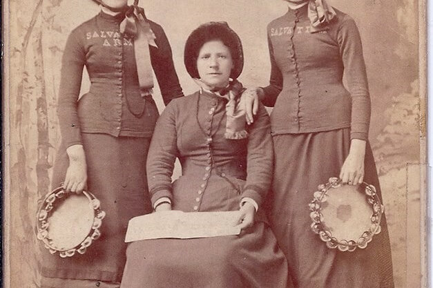 Annie Shirley Seated between Salvation Army Colleagues Portrait of three women in uniform; one sitting and the others to her left and right. The seated woman is holding a document on her lap and the others are holding tambourines. A caption reads, "LIEUT Aldridge; ADJT. Shirley, D.O.; Captain Baker, Lawrence Mass.