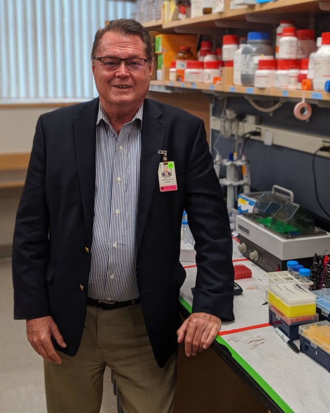 A man in his sixties standing in a medical laboratory.