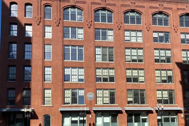 Photograph of a multi-story brick factory building with a facade covered in windows.