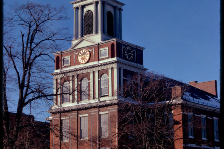 Old_West_Church(BPL) Photograph of a four-story brick church topped by a cupola and weather vane. It is fronted by trees and cars can be seen in the foreground.