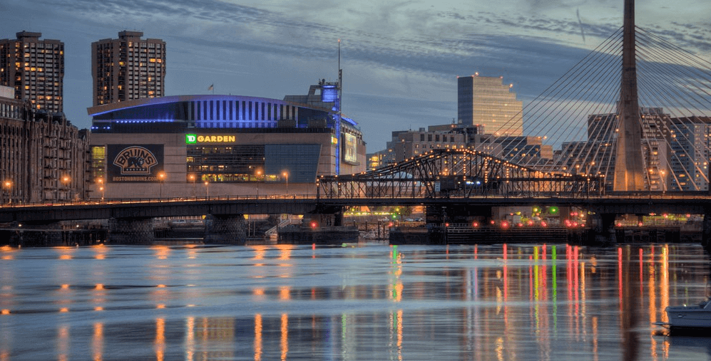 View of a city from across the water, featuring a bridge, sports complex, and hi-rise apartments