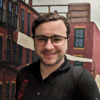 Sebastian Belfanti, a 30 year old white man with a beard, wearing glasses and a black polo shirt