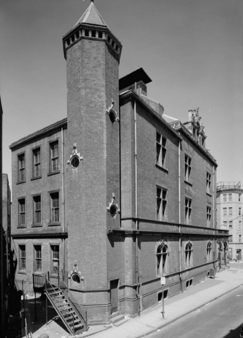 Black and white photograph of an outside view of a school with a tower.