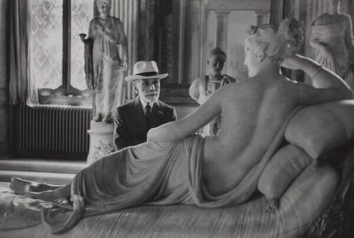 Bernard Berenson at 90 inside a museum gallery. He sits in front of a marble statue of a reclining nude.