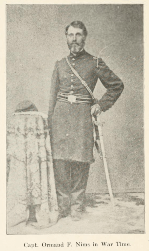 A black and white photograph of Captain Nims, standing and dressed in military gear.