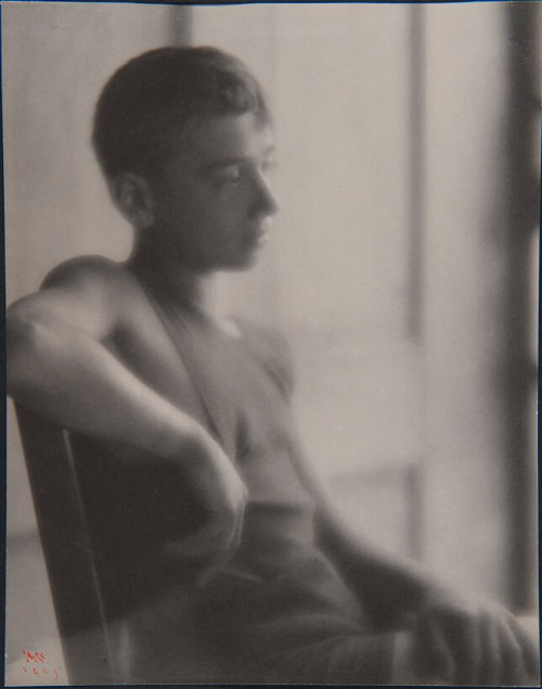 A photograph of a teenage boy in profile visible from the waist up sitting in a chair.