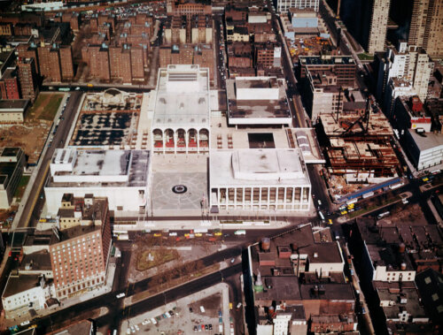An aerial photograph of Lincoln Center in New York, a large white building complex amid more densely packed building spaces.