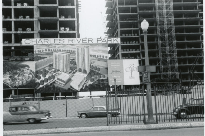 A black and white photograph of two high-rise apartments being built. In front of them is an advertisement for a new apartment complex labelled: "Charles River Park."