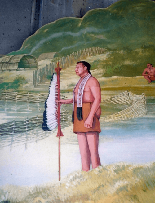 A figure from a mural, dressed in Massachuset tribe traditional clothing, including a hide and a staff.