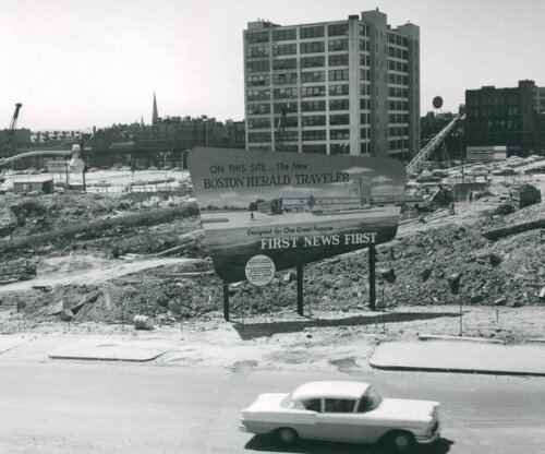 A black and white photograph of a building, with cleared land in the foreground (the other buildings have bee demolished).
