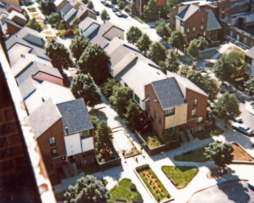 An aerial photograph of three-story brick buildings facing each other, with a garden walkway in the middle.