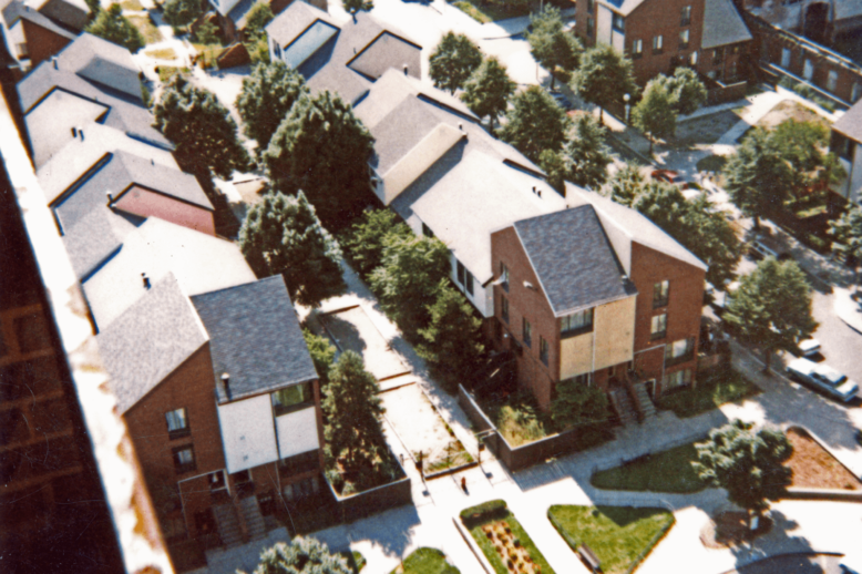 An aerial photograph of three-story brick buildings facing each other, with a garden walkway in the middle.