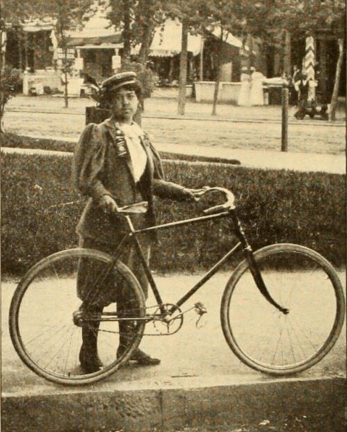 A black and white photograph of a Black woman holding a bicycle.