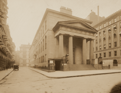 A sepia-toned image of a four-story building fronted by a neoclassical facade.