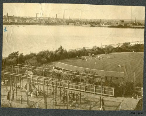 Sepia image of a gymnasium structure and lawn on the edge of a river.