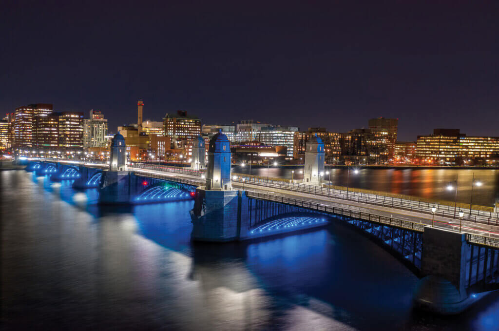 An image of a bridge at night with lights illuminating the towers.