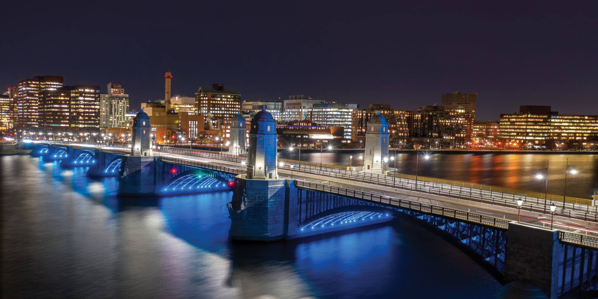 An image of a bridge at night with lights illuminating the towers.