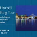 An image of two bridges, a suspension bridge and a smaller pedestrian bridge from a distance. It is night and they are illuminated.