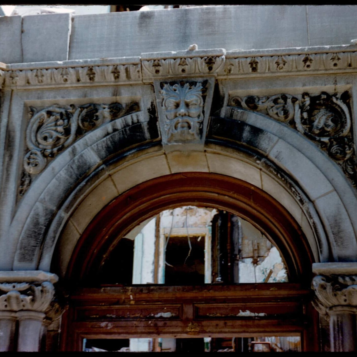A carved stone arch above a door with missing windows.