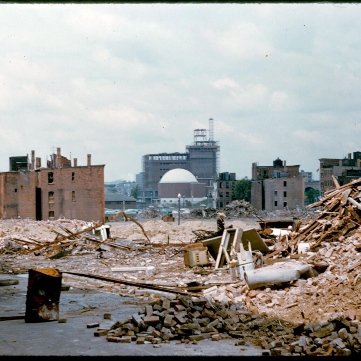 A rubble pile in the foreground with abandoned tenements with the Museum of Science in the distance.