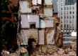 A half demolished building with different rooms with colorful wallpaper visible.
