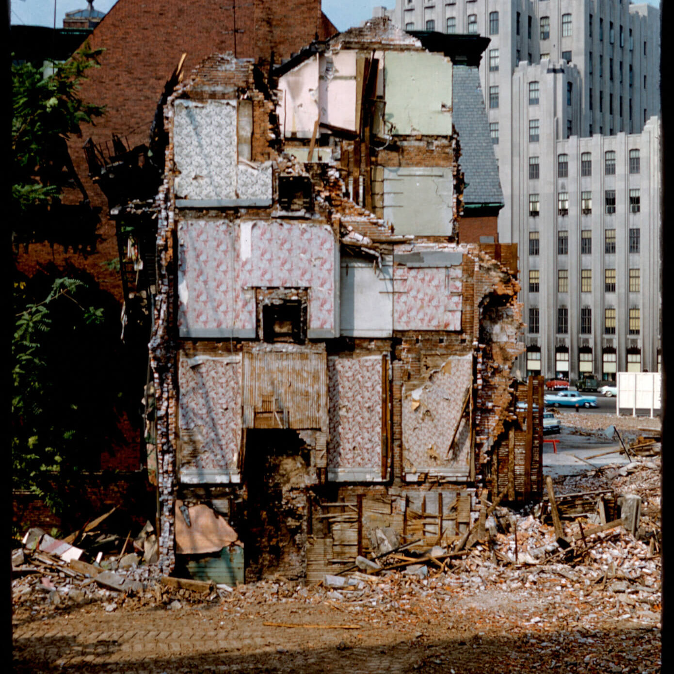 A half demolished building with different rooms with colorful wallpaper visible.