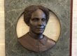 Bronze sculpture bust of a woman in a green marble fram.