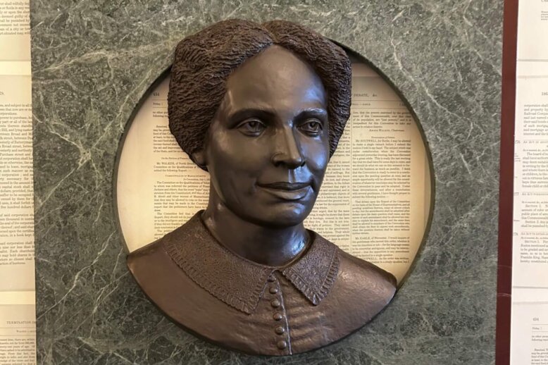 Bronze sculpture bust of a woman in a green marble fram.