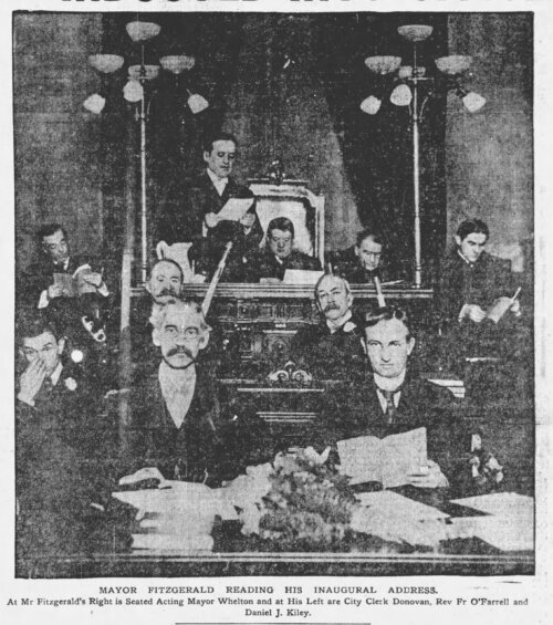 An image of several men facing the camera on the dais of a mayoral office.