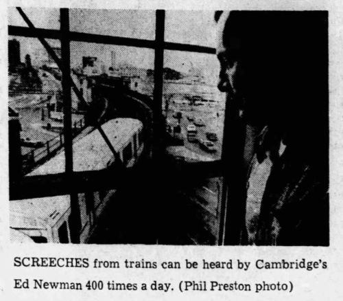 A man looks out a window onto a train passing by.