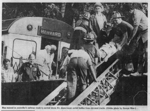 A group of firefighters lower an injured person down off train tracks next to a train.