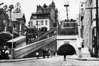 A railway car going up a steep track next to a tunnel.