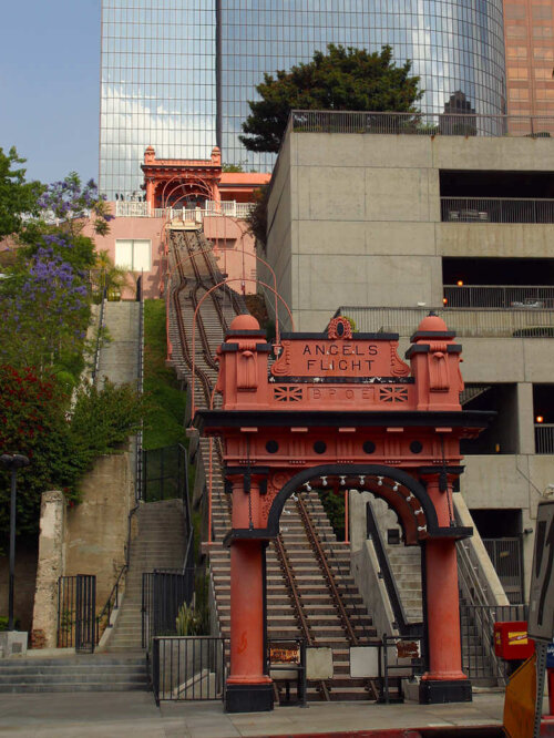 A decorated red archway leading to a steep rail track leading to another arch.