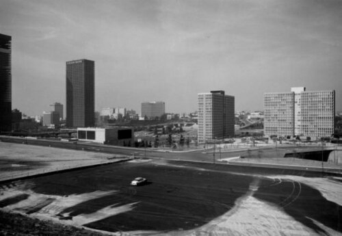 A cleared section of a city with one car in it, surrounded by high rises.