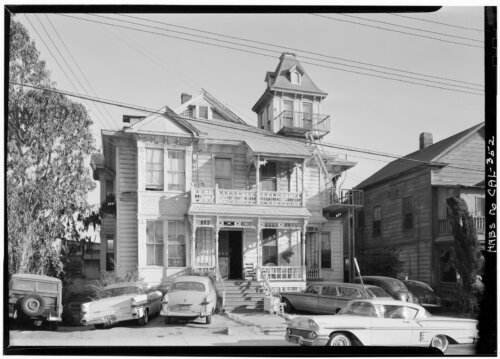 A mansion with a cupola with several cars parked in front.