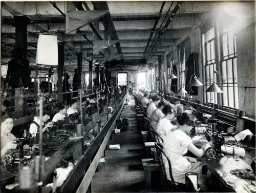 Interior photo of a factory full of women working at sewing machines.