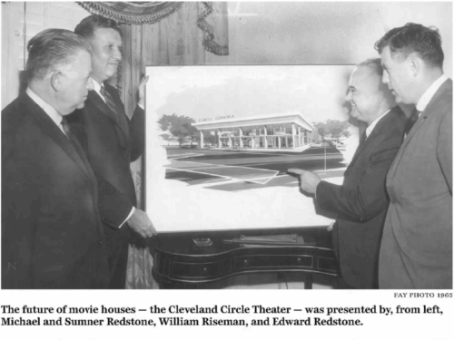Four men standing around an architects rendering of a building.