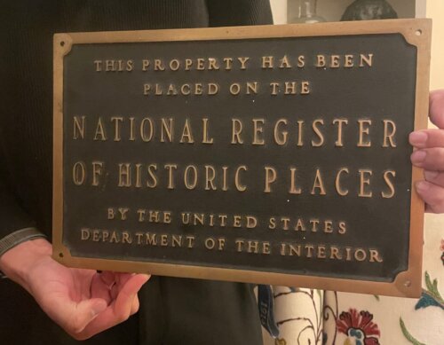 A man holds a plaque that says "National Register of Historic Places".