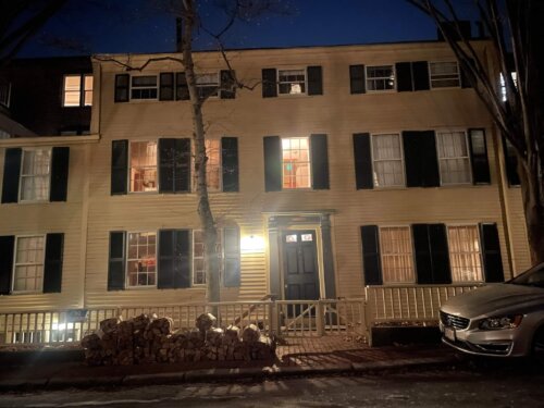 A yellow federalist house at night.
