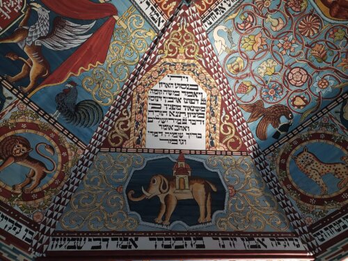A colorful decorated ceiling with Hebrew letters animals and small symbols in circles.