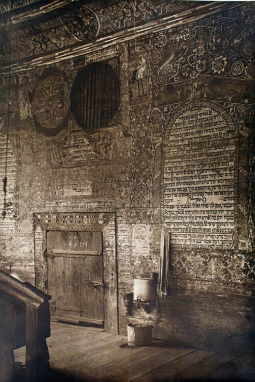 The interior of a synagogue with many elaborate designs painted on the wall.